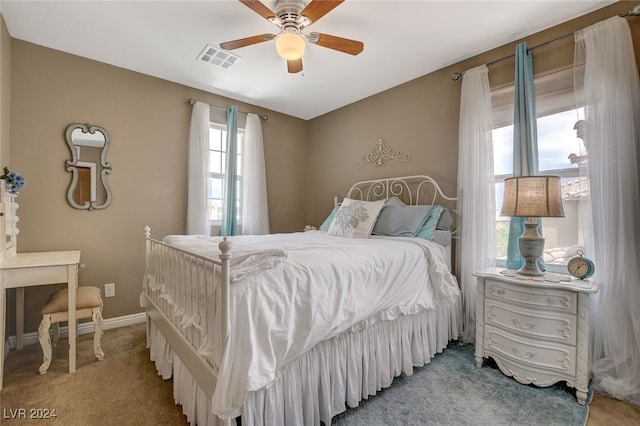 carpeted bedroom featuring multiple windows and ceiling fan