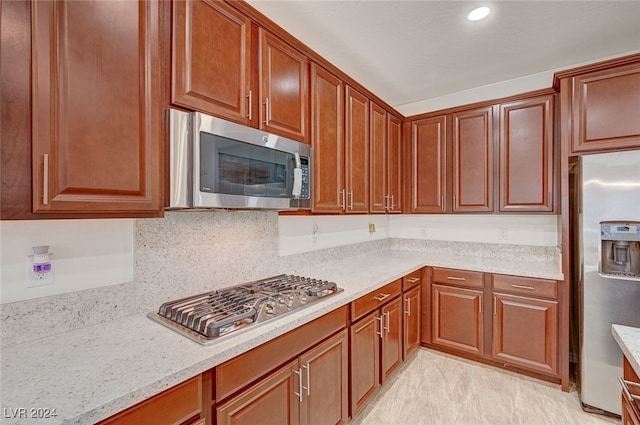 kitchen with light stone counters, appliances with stainless steel finishes, and tasteful backsplash