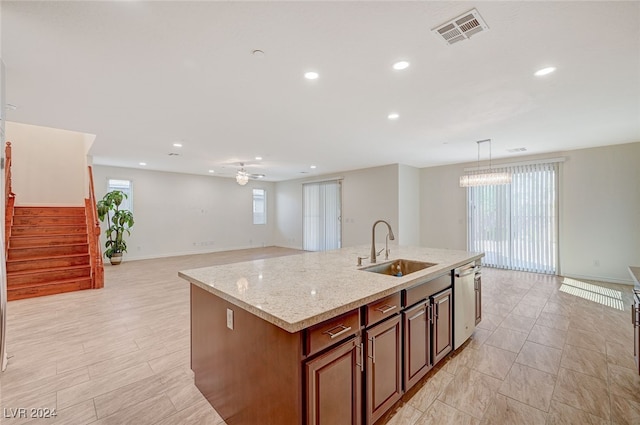 kitchen featuring a healthy amount of sunlight, stainless steel dishwasher, a kitchen island with sink, and sink