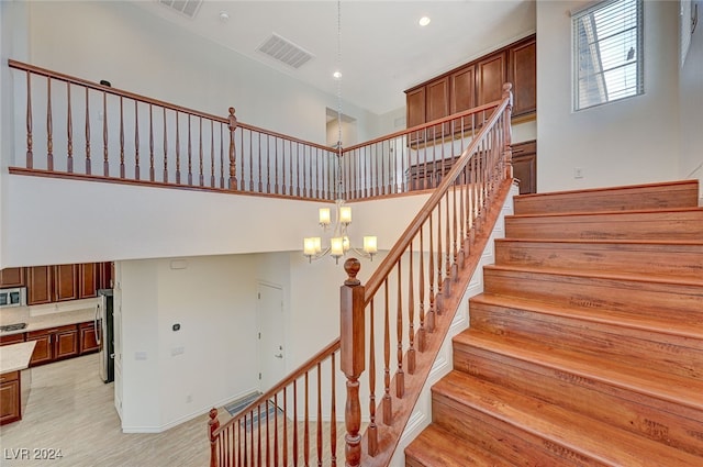 staircase featuring a towering ceiling and a chandelier