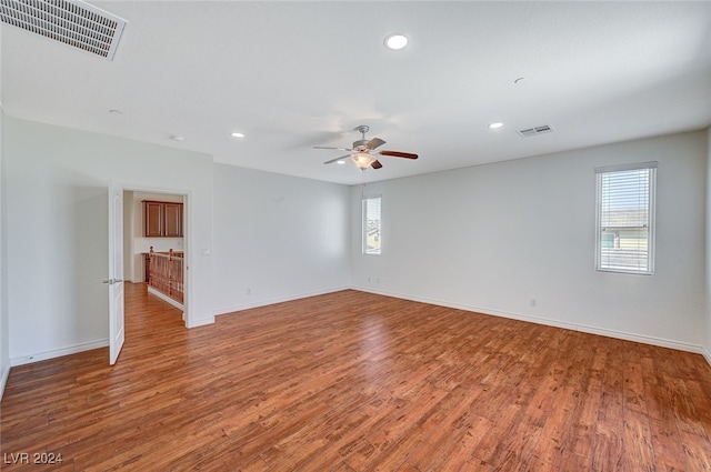 empty room with ceiling fan, wood-type flooring, and a healthy amount of sunlight