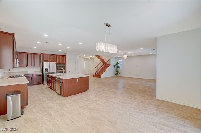 kitchen featuring appliances with stainless steel finishes, pendant lighting, a center island with sink, sink, and a chandelier