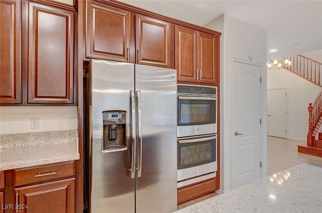 kitchen with stainless steel appliances, light stone counters, and light hardwood / wood-style floors