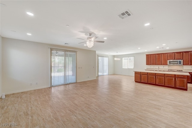 unfurnished living room featuring a healthy amount of sunlight, light hardwood / wood-style floors, sink, and ceiling fan