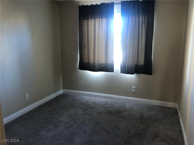 spare room featuring dark colored carpet