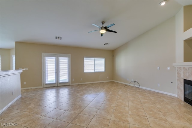 unfurnished living room with french doors, light tile patterned flooring, a tile fireplace, and ceiling fan