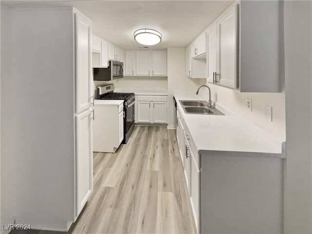 kitchen featuring stainless steel appliances, sink, white cabinets, and light hardwood / wood-style floors