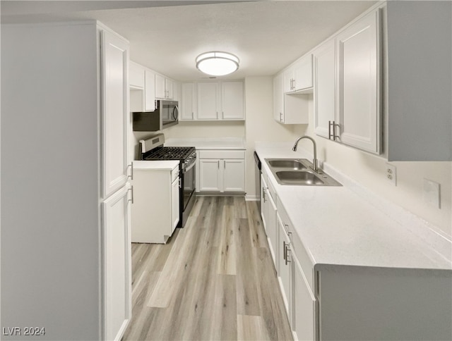 kitchen with white cabinets, appliances with stainless steel finishes, light hardwood / wood-style floors, and sink