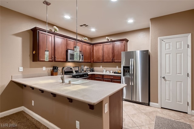 kitchen featuring a breakfast bar, kitchen peninsula, decorative light fixtures, and appliances with stainless steel finishes