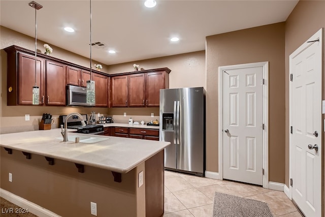 kitchen featuring hanging light fixtures, light tile patterned floors, appliances with stainless steel finishes, sink, and kitchen peninsula