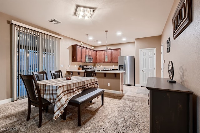 dining space featuring sink and light colored carpet