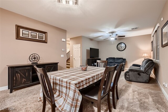 dining space with ceiling fan and light carpet