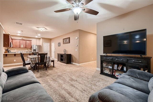 living room featuring ceiling fan, light carpet, and sink