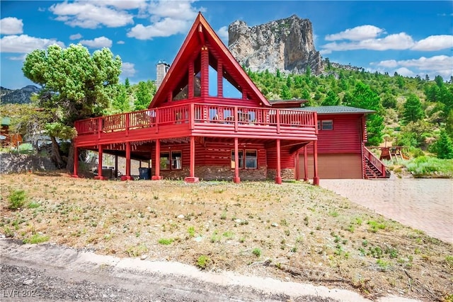 view of front of home with an attached garage, a chimney, driveway, and a deck