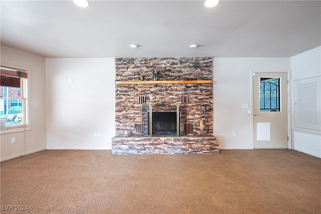 unfurnished living room with a fireplace, a textured ceiling, and carpet floors