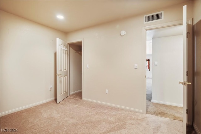 unfurnished bedroom with recessed lighting, a spacious closet, visible vents, baseboards, and light colored carpet