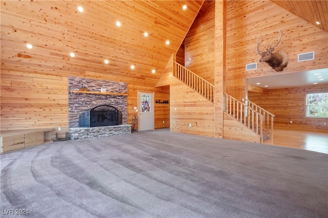 unfurnished living room featuring a fireplace, high vaulted ceiling, wood walls, wood ceiling, and carpet floors