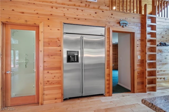 kitchen with built in fridge, hardwood / wood-style floors, and wood walls