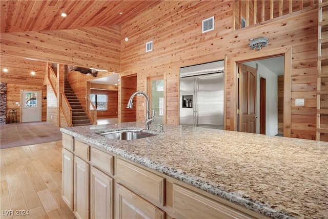 kitchen featuring light hardwood / wood-style flooring, light stone counters, sink, built in fridge, and high vaulted ceiling