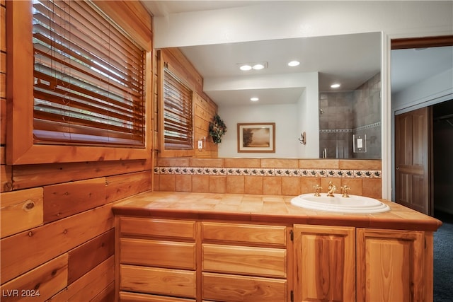 bathroom with tiled shower and vanity