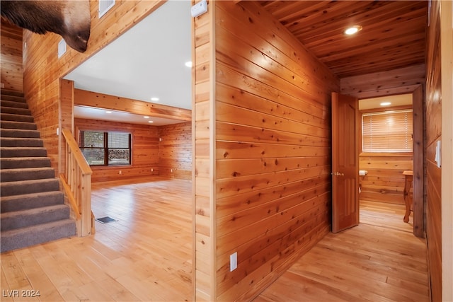 hallway with light wood-type flooring, wood ceiling, and wood walls