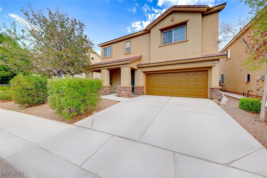 3881 Burma Rd, North Las Vegas, NV 89032 - view of front of property featuring a garage, stucco siding, stone siding, and driveway