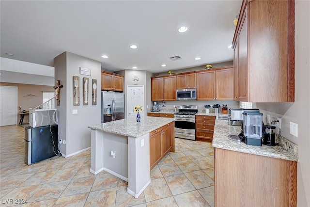 kitchen featuring a kitchen island, stainless steel appliances, and light stone countertops