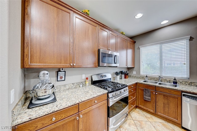 kitchen featuring appliances with stainless steel finishes, light tile patterned flooring, sink, and light stone countertops