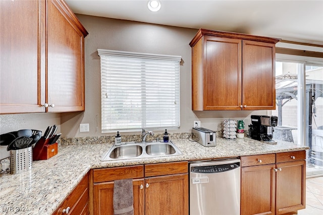 kitchen with light tile patterned floors, light stone counters, sink, and stainless steel dishwasher