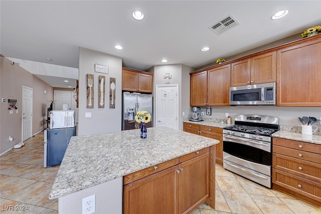 kitchen with light stone counters, a kitchen island, and stainless steel appliances