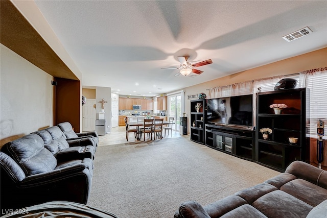 carpeted living room featuring a textured ceiling and ceiling fan