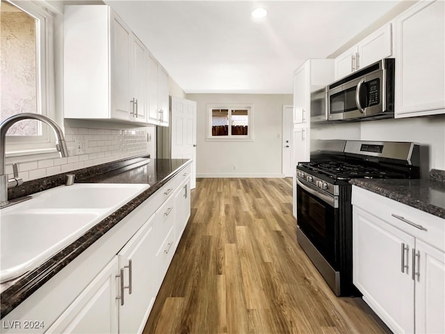 kitchen with hardwood / wood-style flooring, sink, appliances with stainless steel finishes, and white cabinetry