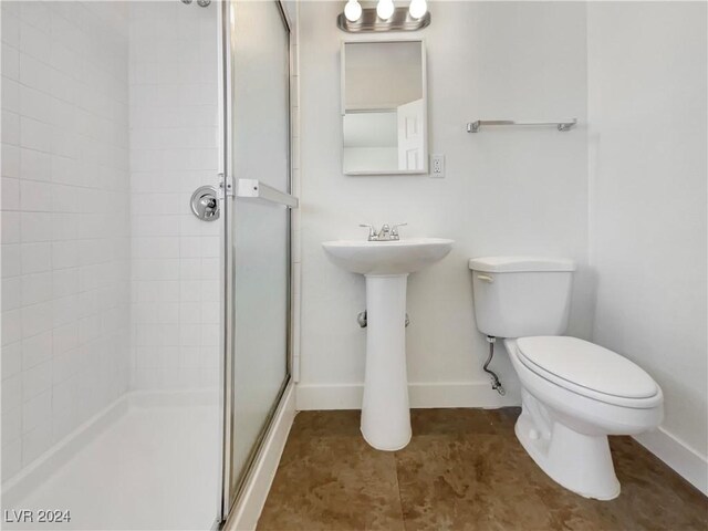 bathroom featuring a shower with shower door and toilet