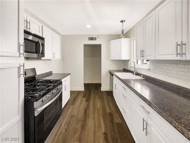 kitchen featuring white cabinets, appliances with stainless steel finishes, sink, dark wood-type flooring, and pendant lighting