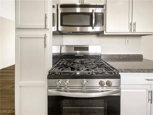 kitchen with wood-type flooring, stainless steel appliances, and white cabinetry