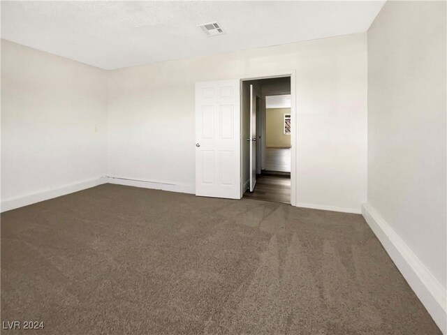 spare room featuring dark carpet