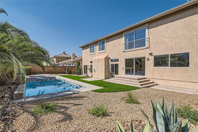 rear view of house with a pool with hot tub and a patio