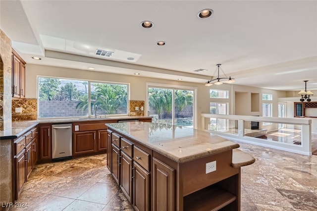 kitchen featuring a kitchen island, decorative light fixtures, decorative backsplash, and a healthy amount of sunlight