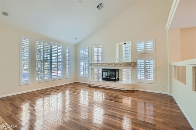 unfurnished living room with high vaulted ceiling, a fireplace, and wood-type flooring