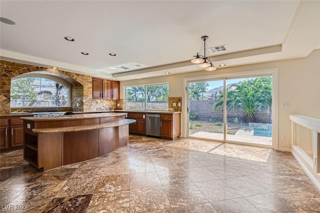 kitchen with stainless steel dishwasher, a center island, decorative light fixtures, a tray ceiling, and backsplash