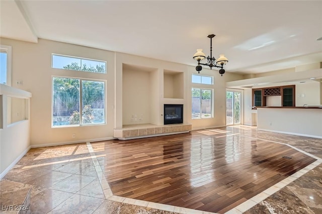 unfurnished living room featuring a fireplace and a chandelier