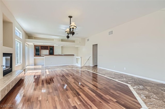 unfurnished living room featuring hardwood / wood-style flooring and a tiled fireplace