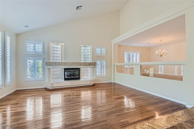 unfurnished living room featuring wood-type flooring, a tile fireplace, an inviting chandelier, and plenty of natural light