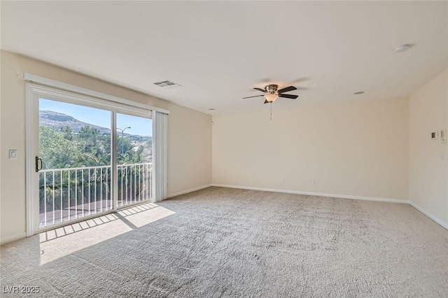 unfurnished room with ceiling fan, a mountain view, and light carpet