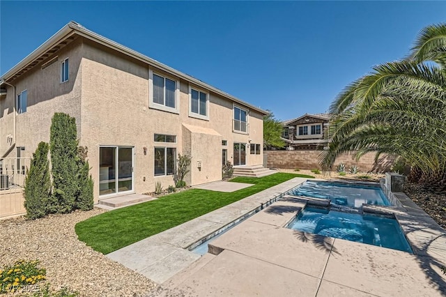 rear view of property with a patio area and a swimming pool with hot tub