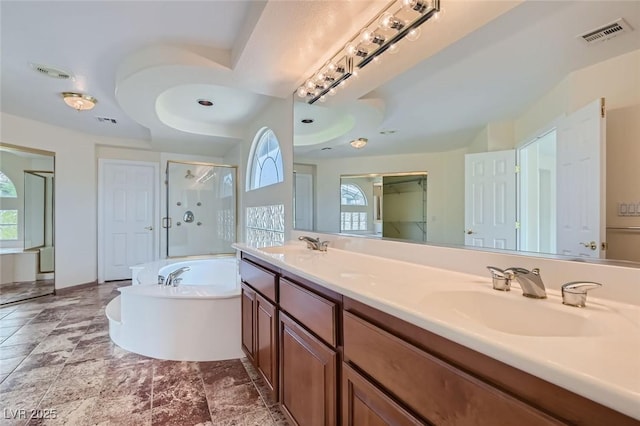 bathroom featuring plus walk in shower, a healthy amount of sunlight, a raised ceiling, and vanity