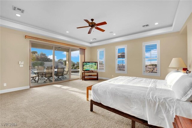 carpeted bedroom featuring a tray ceiling, ceiling fan, and access to outside