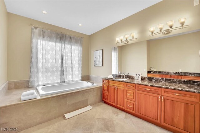 bathroom featuring tile patterned flooring, tiled tub, and vanity