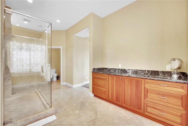 bathroom featuring vanity, toilet, an enclosed shower, and tile patterned flooring