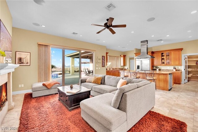 living room with a fireplace, light tile patterned flooring, and ceiling fan